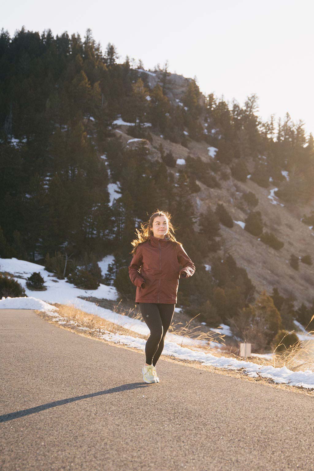 woman running through snowy paved trail